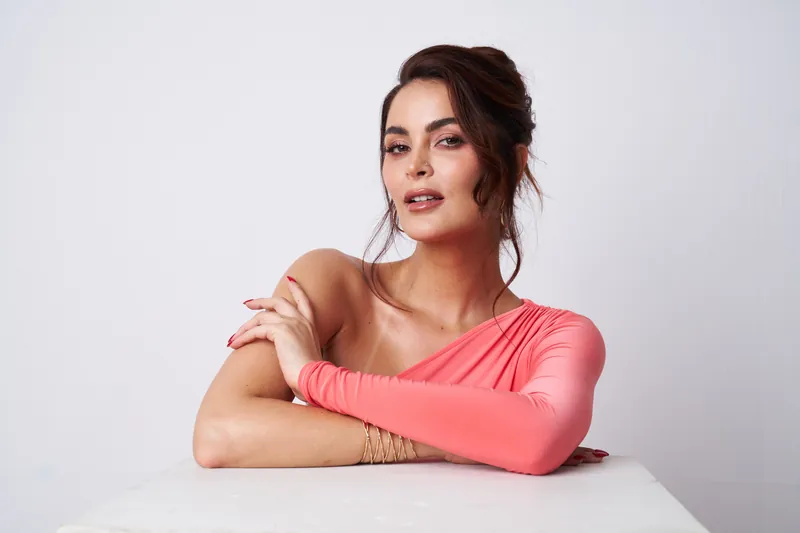 Laura Spoya apoyada sobre una mesa con top coral